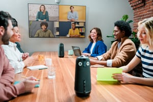People having a meeting in a conference room while half the attendees are on a VC screen